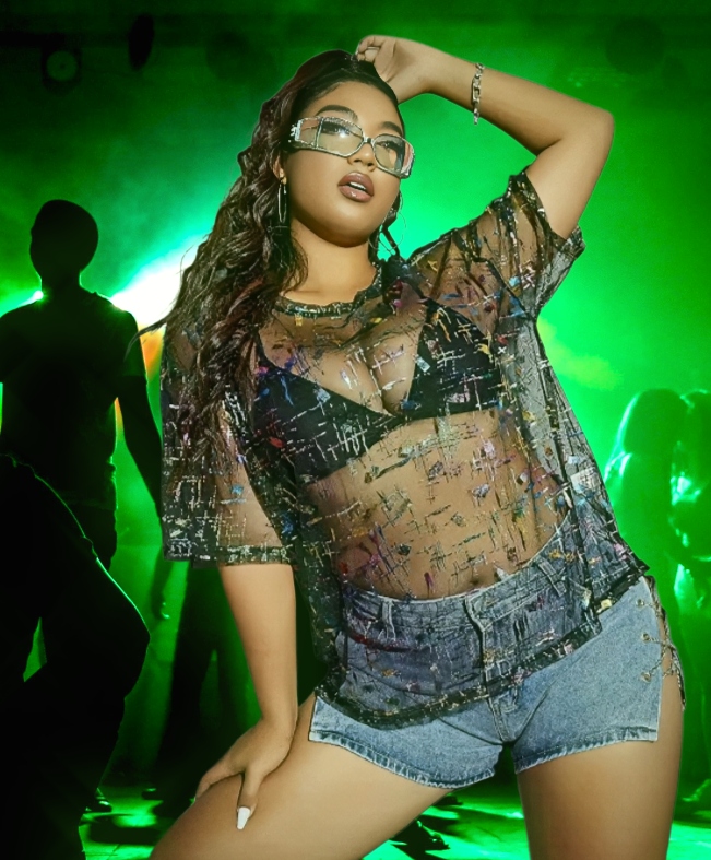 Our Rave Cave model in a shimmering mesh top and denim shorts, surrounded by emerald light